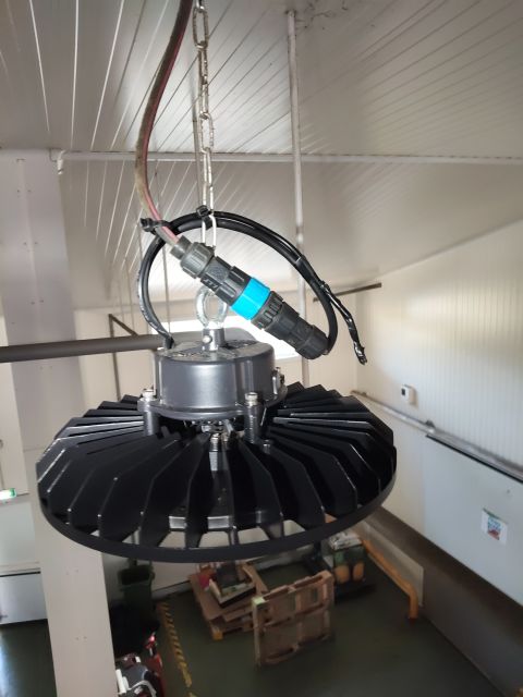 Pose d'un luminaire LED high bay suspendu dans l'entrepôt