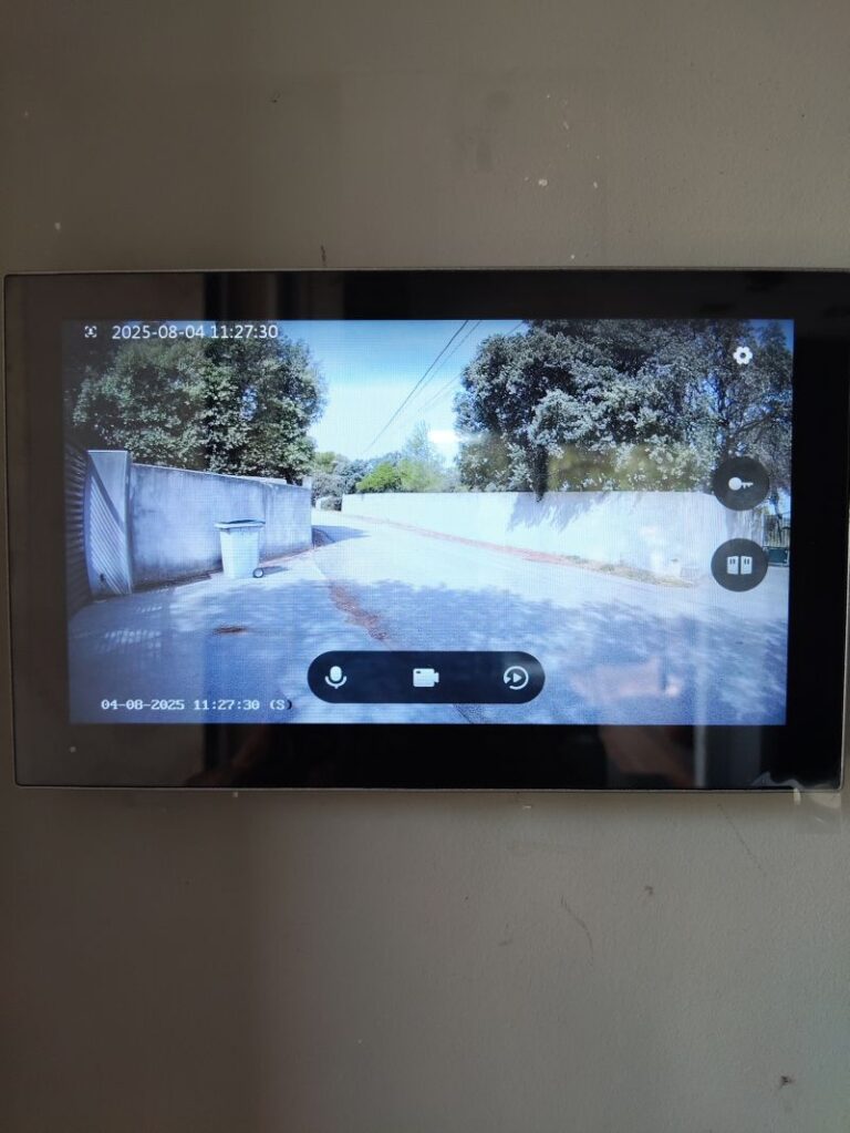 Écran de vidéophone connecté affichant l'entrée et le portail d'une maison